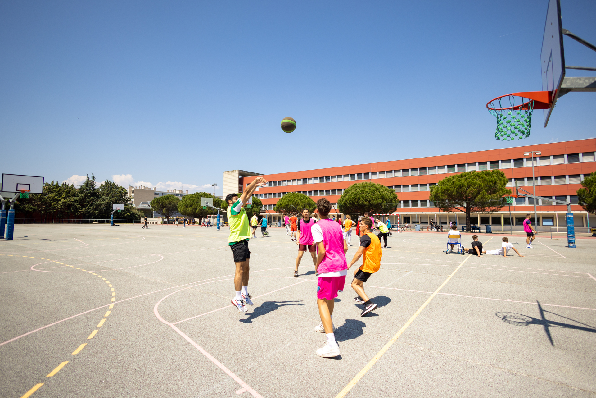 Des lycéens jouent au basket dans la cour du lycée